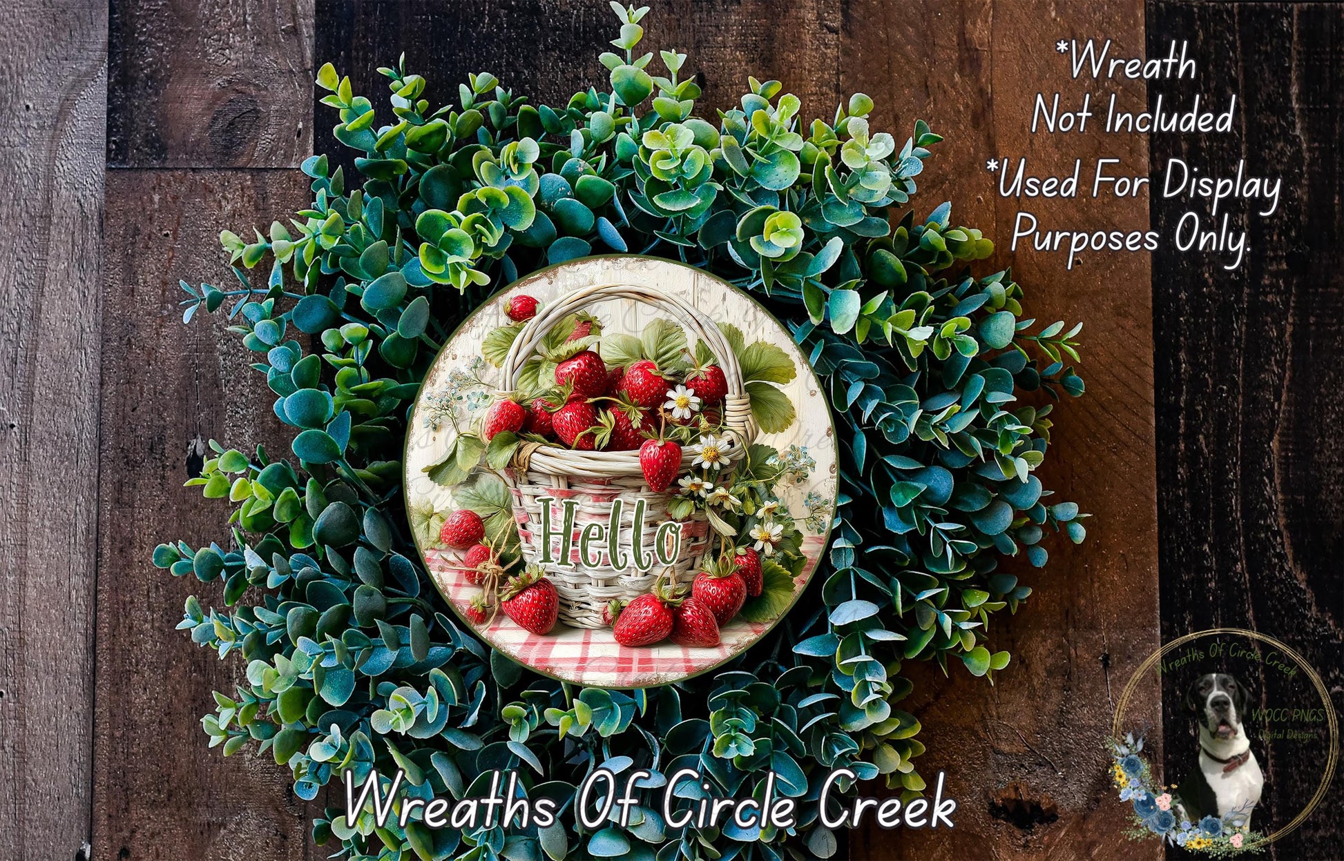 a wreath made of various green plants and a basket of red strawberries, with the word "Hello" written on it. The wreath is displayed on a wooden surface, and there is a small dog in the bottom right corner of the image.
