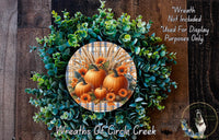 a wreath made of various autumn-themed elements, including pumpkins, flowers, and greenery, set against a wooden background.