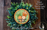 a wreath made of green and orange leaves, with a decorative orange and green sign that reads "Icarot wait for Easter".