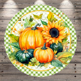 A round, green and white checkered plate with a vibrant arrangement of autumn-themed pumpkins and a sunflower on it, set against a rustic wooden background.