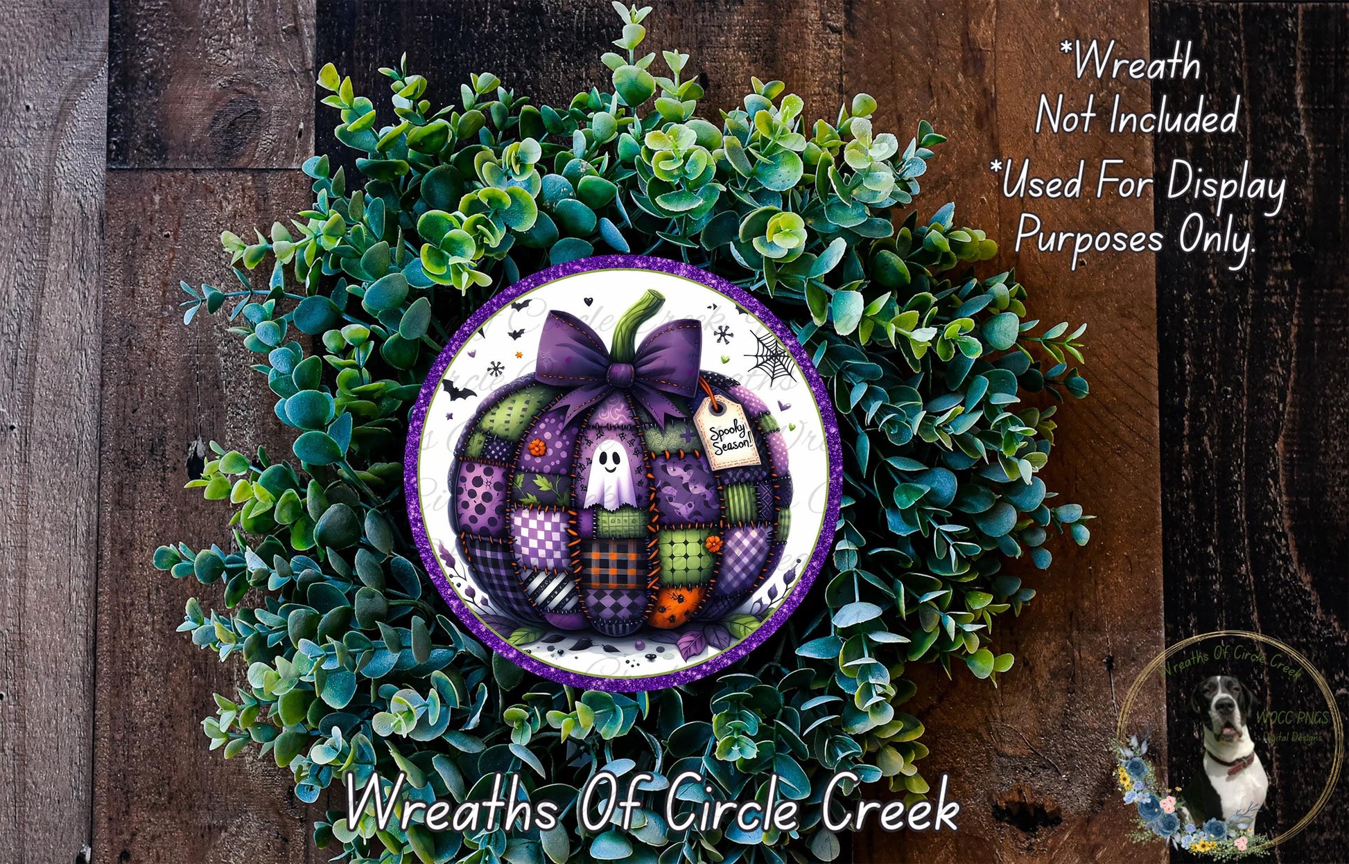 a wreath made of various green plants and a purple pumpkin with a bow, placed on a wooden surface.