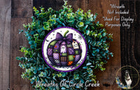 a wreath made of various green plants and a purple pumpkin with a bow, placed on a wooden surface.