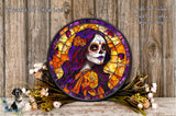 a colorful stained glass portrait of a woman with a skull-like face, surrounded by flowers and placed on a wooden surface.
