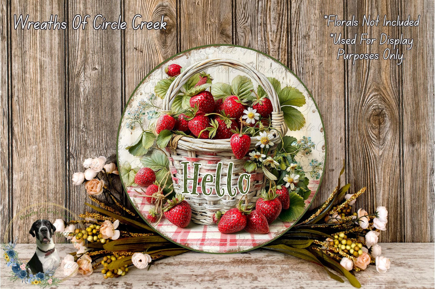 A decorative plate with a basket of fresh strawberries and flowers, including the word "Hello" written on it, placed on a wooden surface.