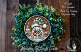 A wreath made of green foliage and featuring a smiling gnome wearing a blue and white hat, with the text "Let it snow" and "Wreaths of Circle Creek" displayed.