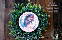 a wreath made of green foliage and a circular design with a fish and the text "Gone Fishing" on it. The wreath is displayed on a wooden surface, and there is a small dog visible in the bottom right corner of the image.