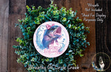 a wreath made of green foliage and a circular design with a fish and the text "Gone Fishing" on it. The wreath is displayed on a wooden surface, and there is a small dog visible in the bottom right corner of the image.