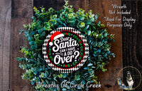 a Christmas wreath made of green leaves and a Santa Claus sign, with the text "Dear Santa, can I have a do over?" displayed on the wreath.