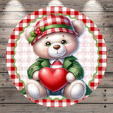 A white teddy bear wearing a red and white plaid hat and holding a red heart, set against a red and white checkered background.