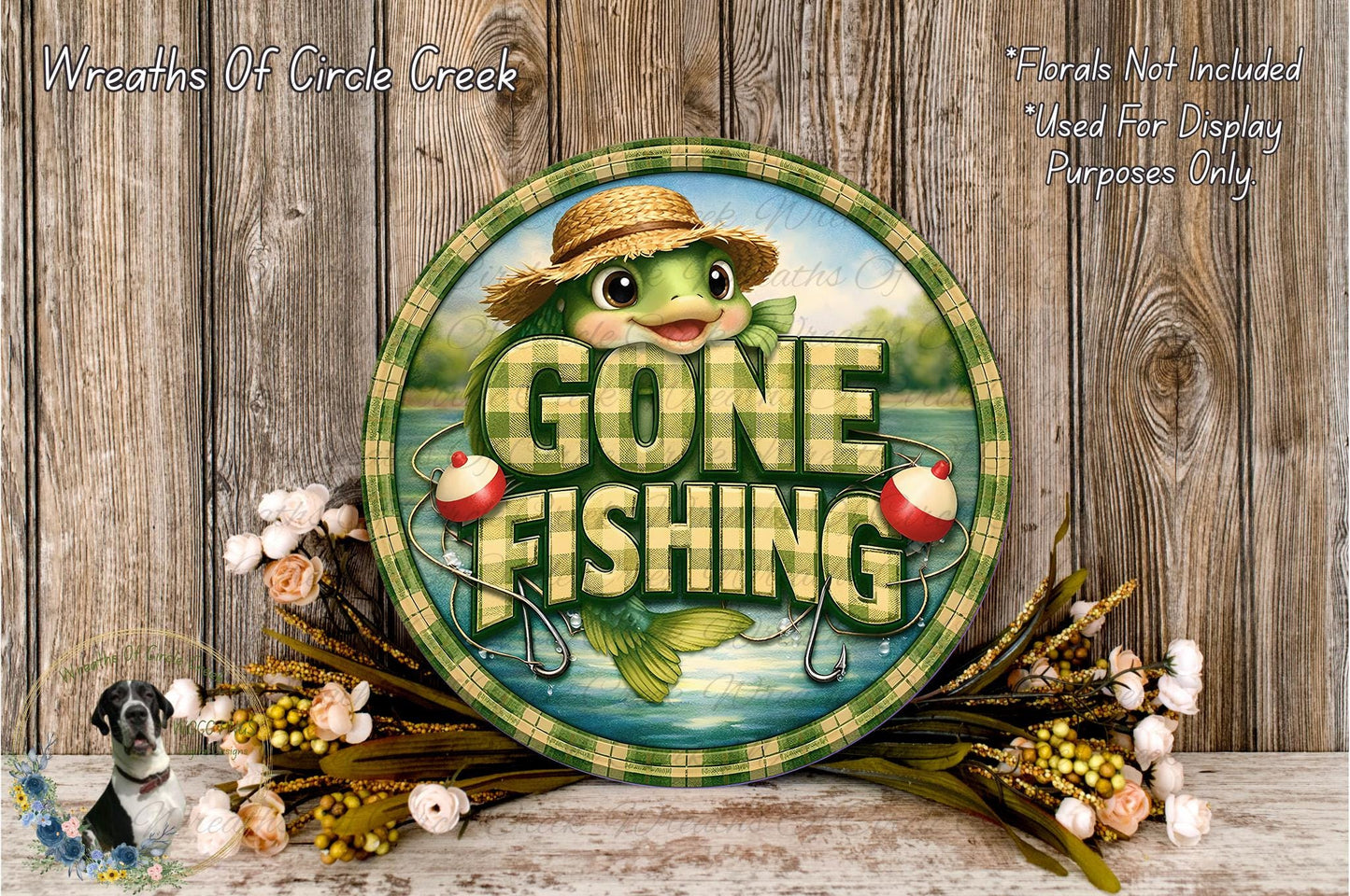 a round sign with the text "GONE FISHING" and a cartoon fish wearing a straw hat. The sign is surrounded by flowers and placed on a wooden surface.
