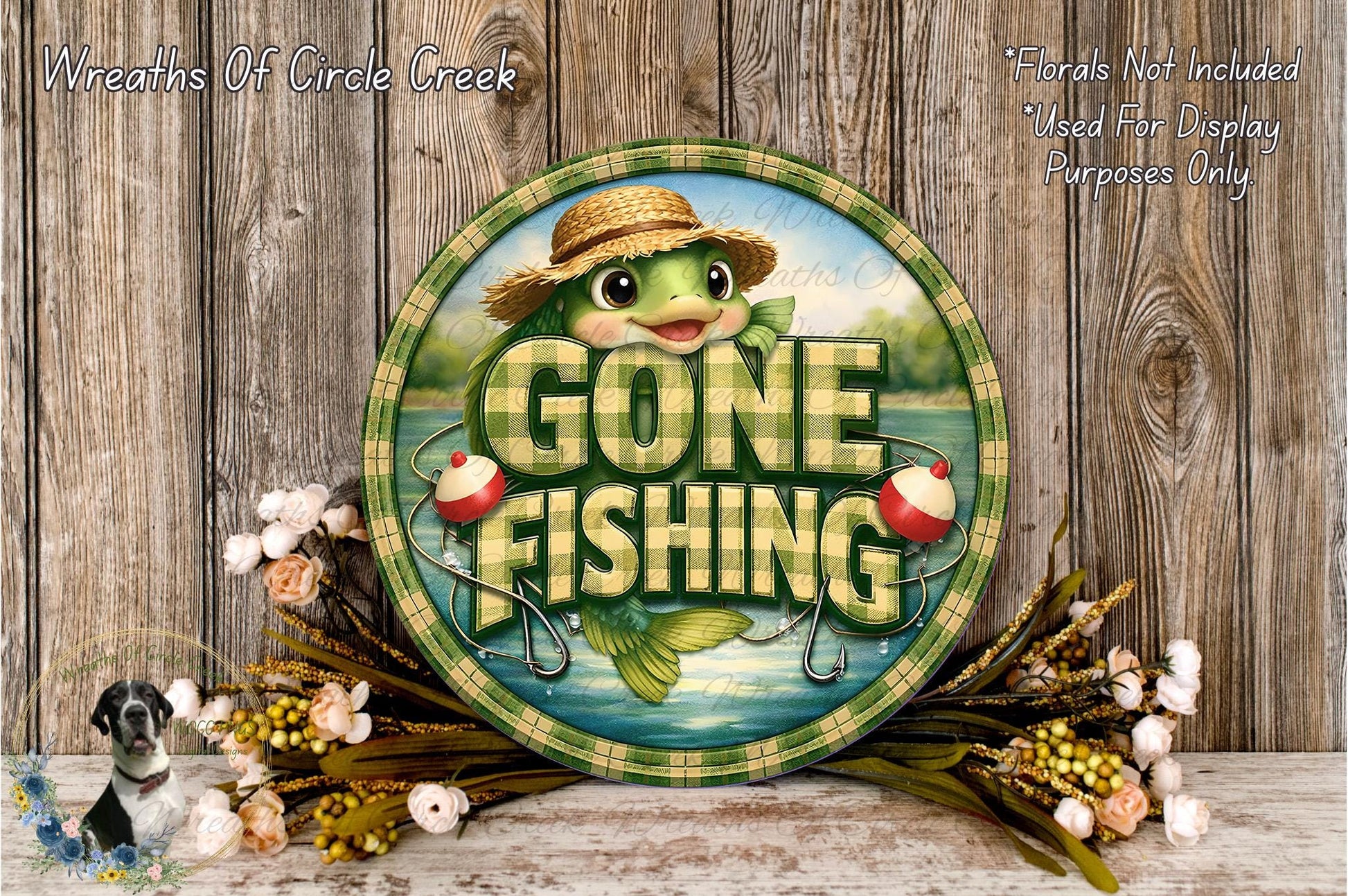 a round sign with the text "GONE FISHING" and a cartoon fish wearing a straw hat. The sign is surrounded by flowers and placed on a wooden surface.