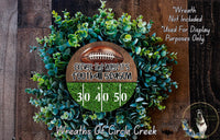 a wreath made of green foliage and a football, with text and numbers displayed on it.