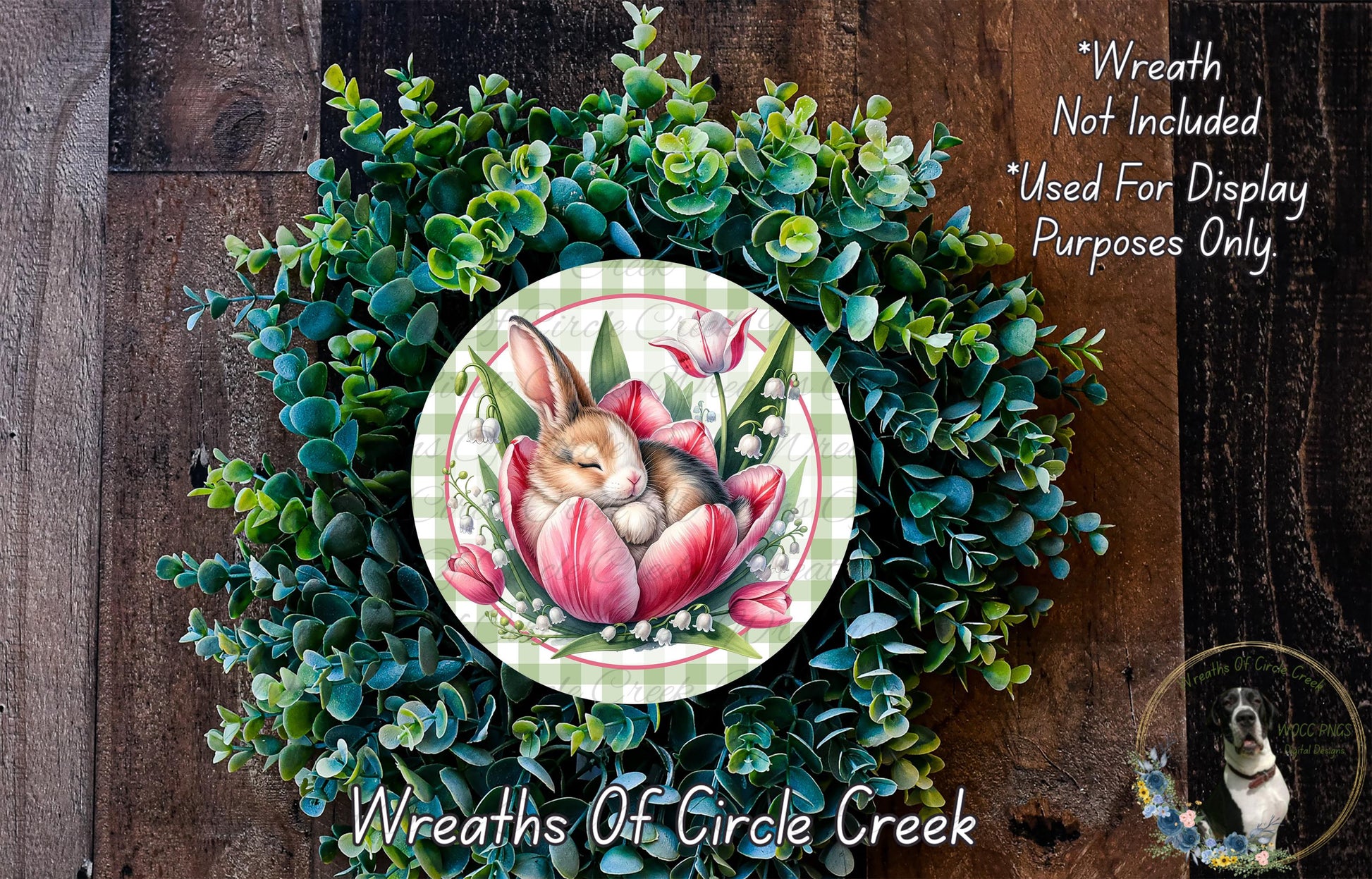 a wreath with a rabbit and a flower, surrounded by greenery. The wreath is placed on a wooden surface.