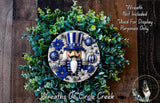 A wreath featuring a nutcracker nutcracker surrounded by blue and white ornaments, greenery, and a dog in the corner.
