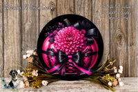 a decorative arrangement of a pink flower on a black background, surrounded by a lace-up design and a ribbon. The arrangement is placed on a wooden surface, with additional flowers and greenery visible in the background.