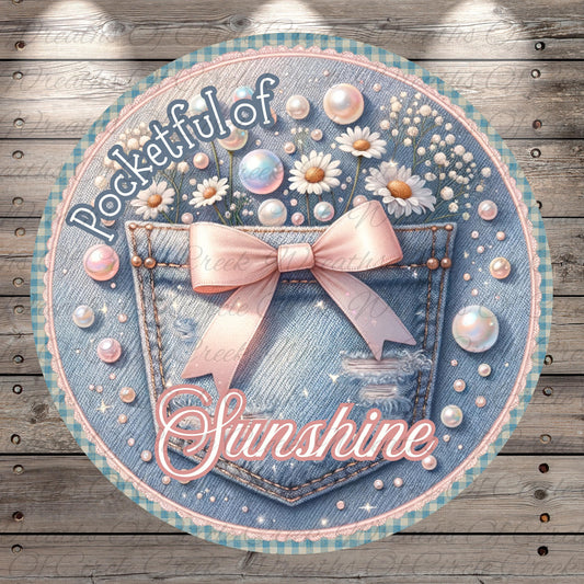 A round, decorative image featuring a denim pocket with a pink bow, surrounded by various decorative elements such as flowers, pearls, and bubbles. The text "Pocketful of Sunshine" is prominently displayed, suggesting a cheerful and uplifting theme.