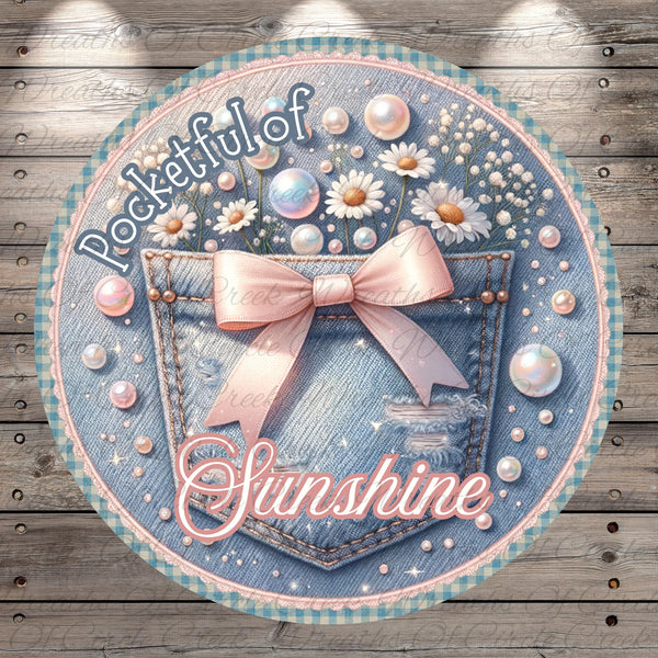 A round, decorative image featuring a denim pocket with a pink bow, surrounded by various decorative elements such as flowers, pearls, and bubbles. The text "Pocketful of Sunshine" is prominently displayed, suggesting a cheerful and uplifting theme.