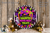 a Halloween-themed decoration with a ghost, a bucket of candy, and a sign that says "Haunt Movie Night Treats". The decoration is set against a wooden background, and there are some flowers and greenery surrounding it.