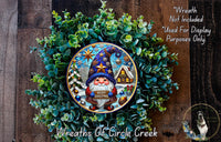 A wreath featuring a gnome holding a "Merry Christmas" sign, surrounded by greenery and a snowy landscape.