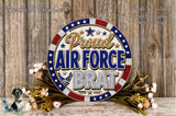 a patriotic wreath with the text "Proud Air Force Brat" displayed prominently. The wreath is surrounded by flowers, and the background is a wooden wall.