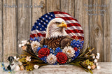 A patriotic wreath featuring an eagle surrounded by flowers, including red, white, and blue flowers, against a wooden background.