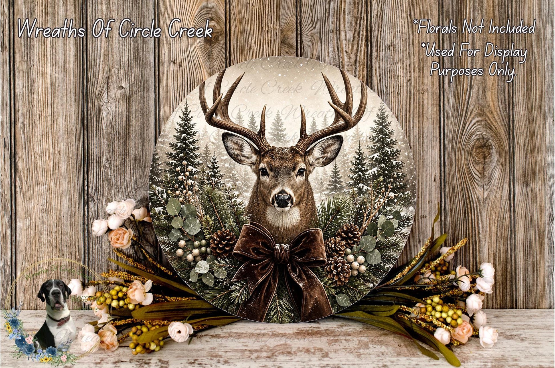 A deer head is displayed in a wreath, surrounded by pine trees, flowers, and a brown ribbon bow.