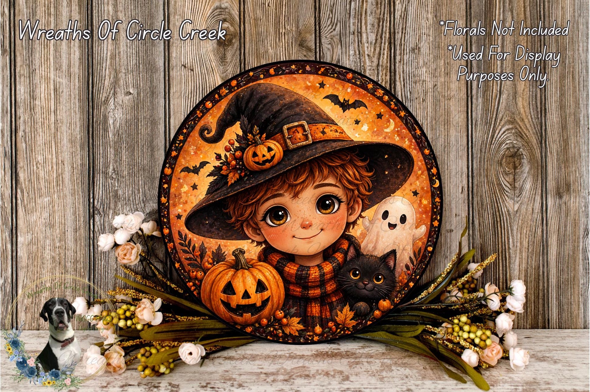 A round, decorative wreath featuring a young girl wearing a witch's hat, holding a pumpkin and a cat, surrounded by autumn foliage and flowers.