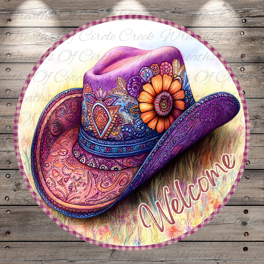 A colorful, intricately decorated cowboy hat with a flower on the side, placed on a circular sign with the word "Welcome" written on it.