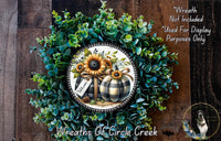 a wreath made of various green and brown foliage, including sunflowers and pumpkins, with a decorative plate in the center displaying a welcoming message.