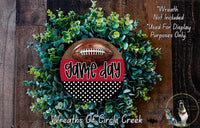 a wreath made of green foliage and a football, with the word "game day" written on it. The wreath is displayed on a wooden surface, and there is a text overlay that reads "Wreath Not Included * Used For Display Purposes Only".