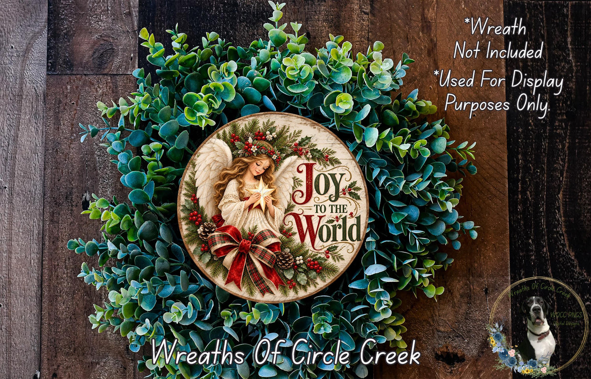 a wreath with a central design of an angel holding a star, surrounded by a lush green wreath. The wreath is displayed on a wooden surface, and there is a small dog in the bottom right corner of the image.