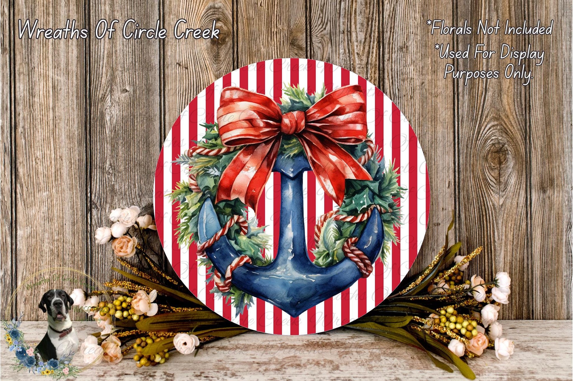 a round wreath with a blue anchor and red ribbon, surrounded by a variety of flowers and greenery, placed on a wooden surface.