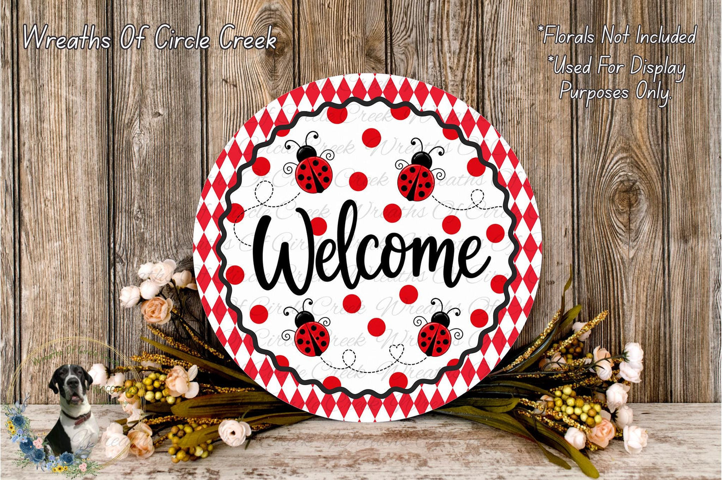a decorative welcome sign with a red and white polka dot pattern, surrounded by a floral arrangement and a wooden background.