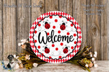 a decorative welcome sign with a red and white polka dot pattern, surrounded by a floral arrangement and a wooden background.