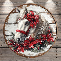 A white horse adorned with a red bow and surrounded by red poinsettia flowers and pine branches, set against a snowy background.