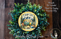 A wreath made of green foliage and featuring a yellow and green RV design, with the text "CAMP LIFE" and "Weights of Circle Creek" printed on it.