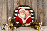 A festive wreath featuring Santa Claus and his grandmother, surrounded by holiday decorations such as flowers and greenery, set against a wooden background.