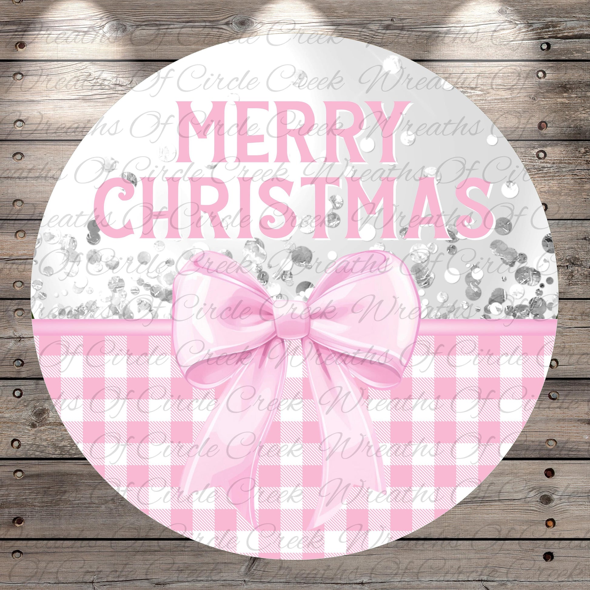 A circular sign with the text "Merry Christmas" in pink letters, surrounded by a pink bow and a gingham pattern.