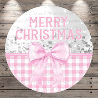 A circular sign with the text "Merry Christmas" in pink letters, surrounded by a pink bow and a gingham pattern.