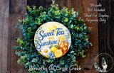 a wreath made of green leaves and flowers, with a circular sign in the center that says "Sweet Tea and Sunshine".