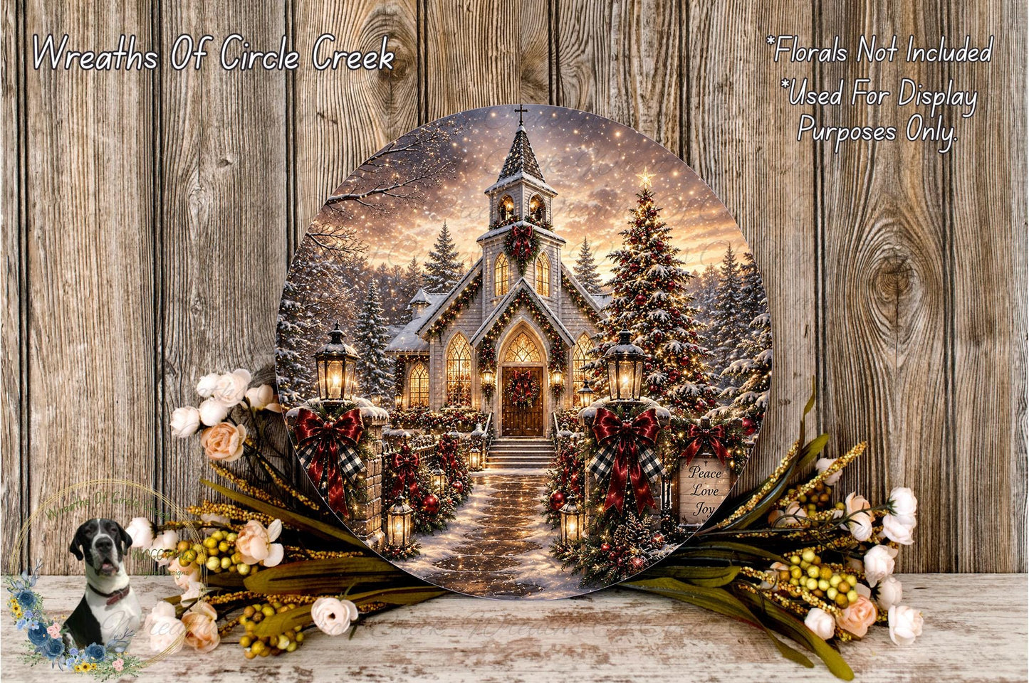 A round wooden plaque displaying a winter scene of a church with a bell tower, surrounded by Christmas decorations and flowers.