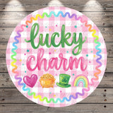a circular design with the text "lucky charm" written in a cursive font. The design is surrounded by a border of colorful ribbons and includes illustrations of a pot of gold coins, a rainbow, and a leprechaun hat.