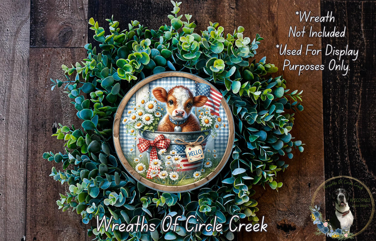 a wreath with a cow sitting in a bucket, surrounded by green foliage and flowers. The wreath is displayed on a wooden surface, and there is a small dog visible in the bottom right corner of the image.