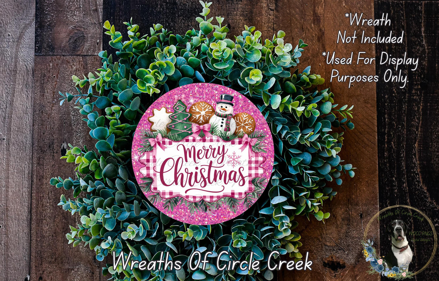 A Christmas wreath made of evergreen branches and a pink circular sign with the text "Merry Christmas" and a snowman decoration.
