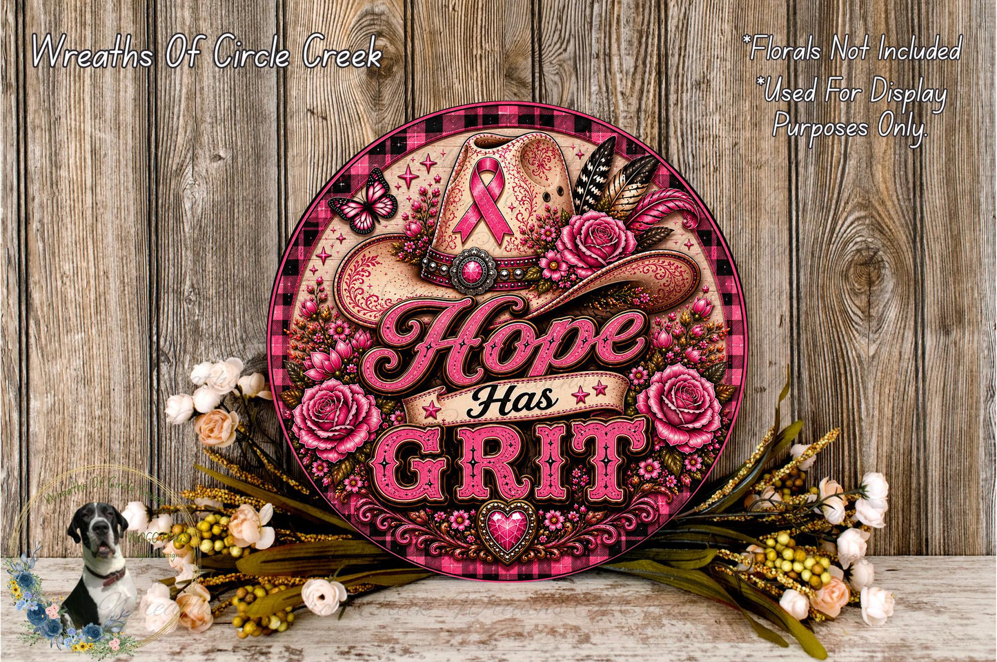a decorative sign with the text "Hope Has Grit" surrounded by pink and white floral elements, including roses and a cowboy hat. The sign is placed on a wooden surface, and there are also some flowers and greenery in the foreground.