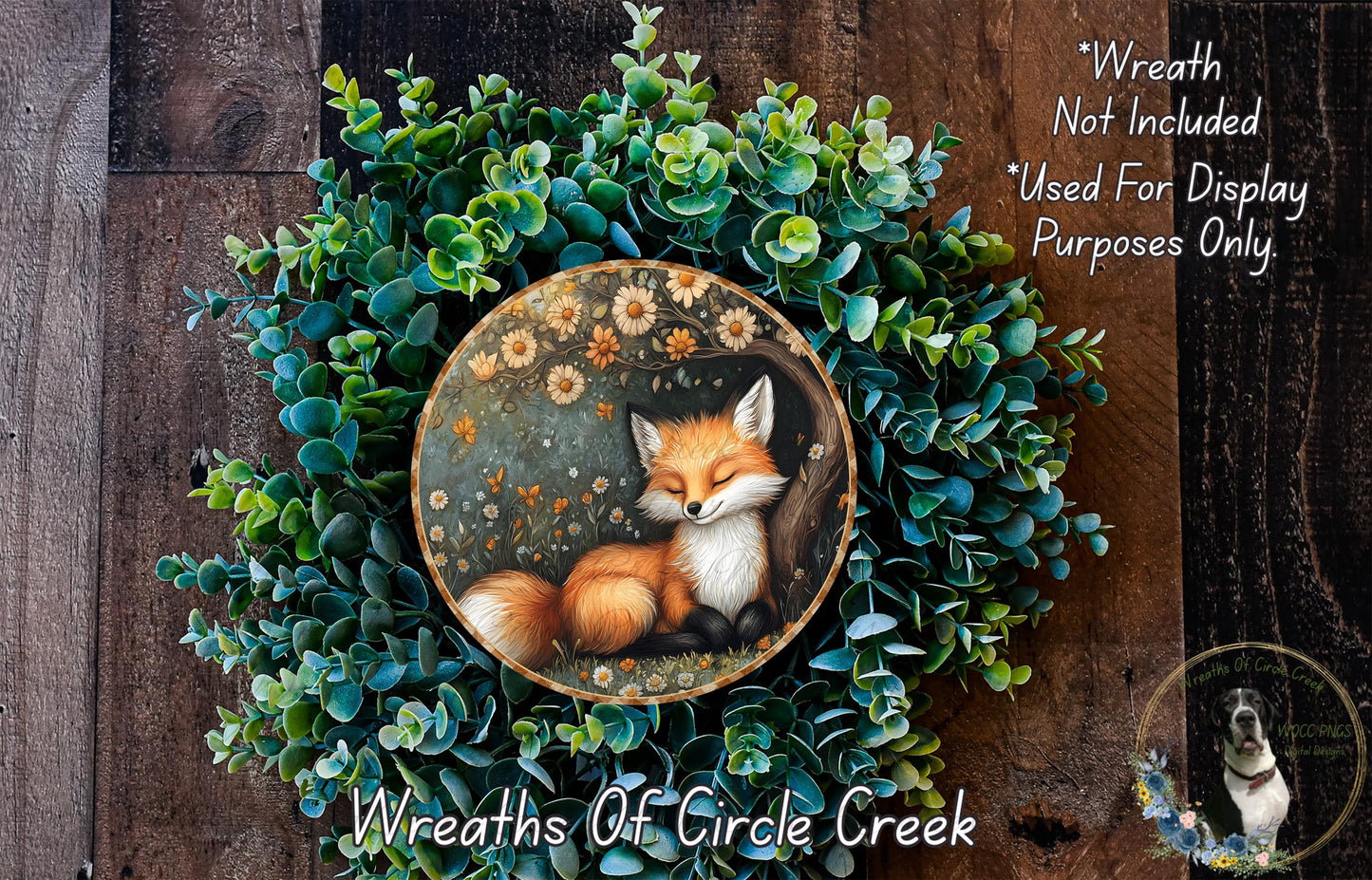 A wreath made of green foliage and flowers, with a painted image of a sleeping fox in the center.