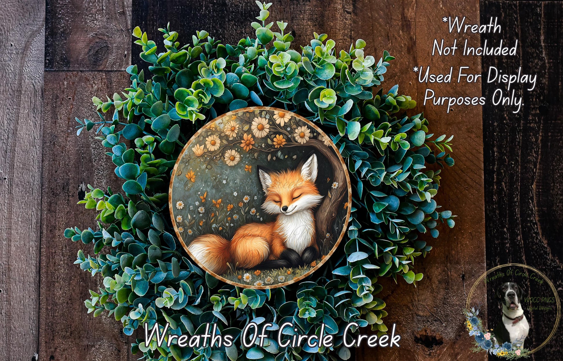 A wreath made of green foliage and flowers, with a painted image of a sleeping fox in the center.