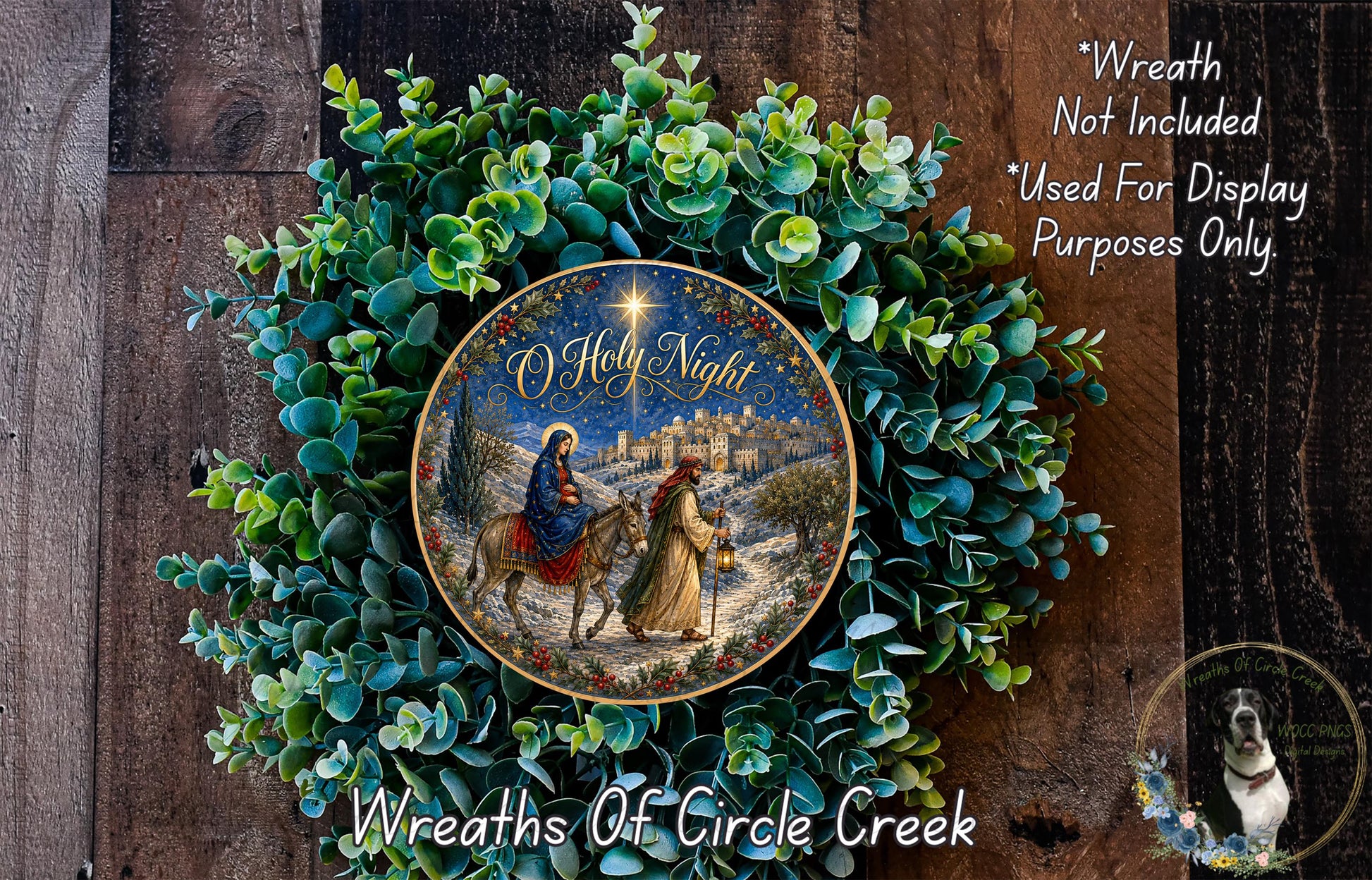 A wreath with a Christmas scene featuring a nativity scene, including a figure of Mary, baby Jesus, and two men on horseback. The wreath is surrounded by greenery and has a decorative plate with a Christmas scene on it.