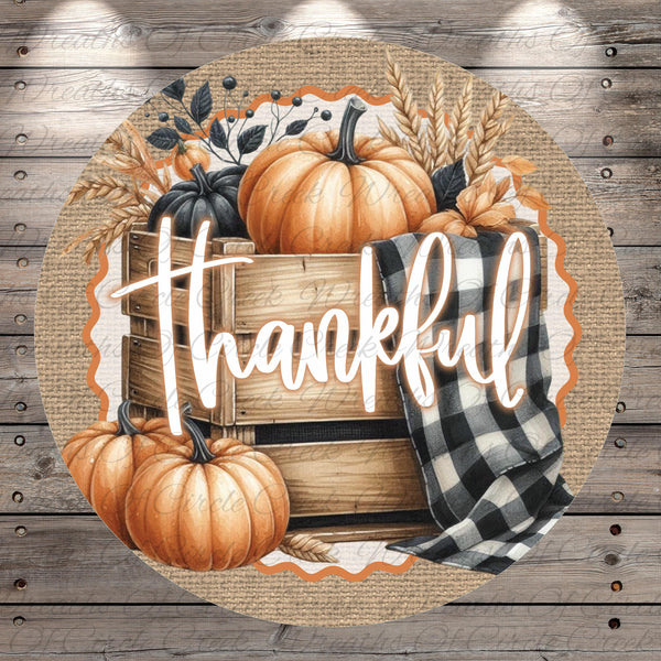 A circular graphic with a wooden crate, pumpkins, and a black and white checkered cloth, along with the word "Thankful" written in cursive.