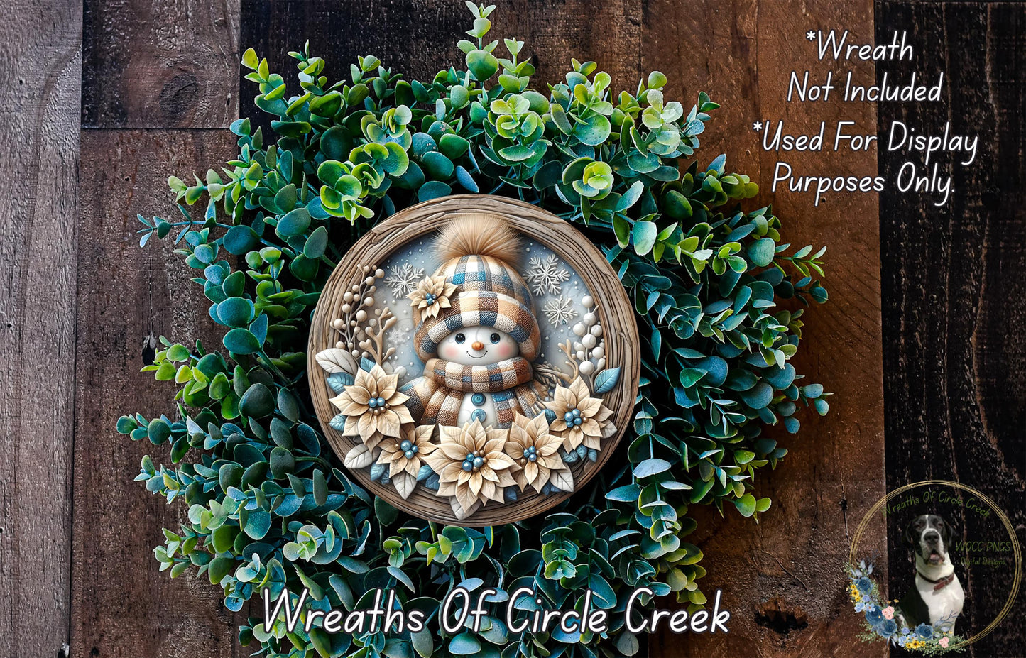 A wreath with a snowman and flowers, surrounded by greenery, is displayed on a wooden surface.